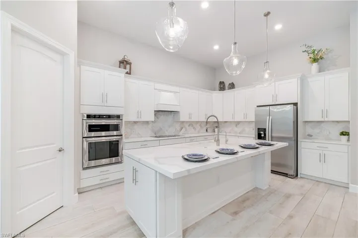Kitchen with white cabinets, appliances with stainless steel finishes, backsplash, premium range hood, and recessed lighting
