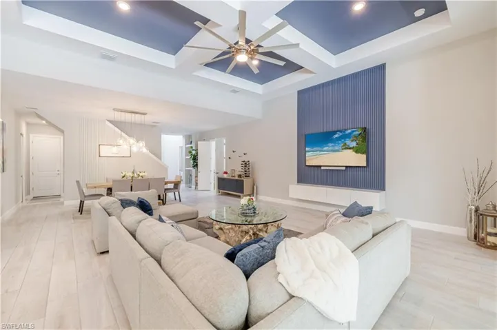 Living area with coffered ceiling, a chandelier, ceiling fan, light wood-style floors, and beam ceiling