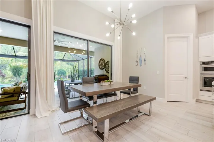 Dining space featuring a chandelier, a sunroom, a ceiling fan, and light wood-style floors