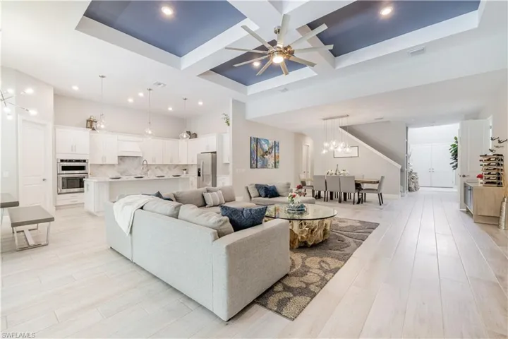 Living area featuring coffered ceiling, beamed ceiling, a chandelier, light wood-style flooring, and a ceiling fan