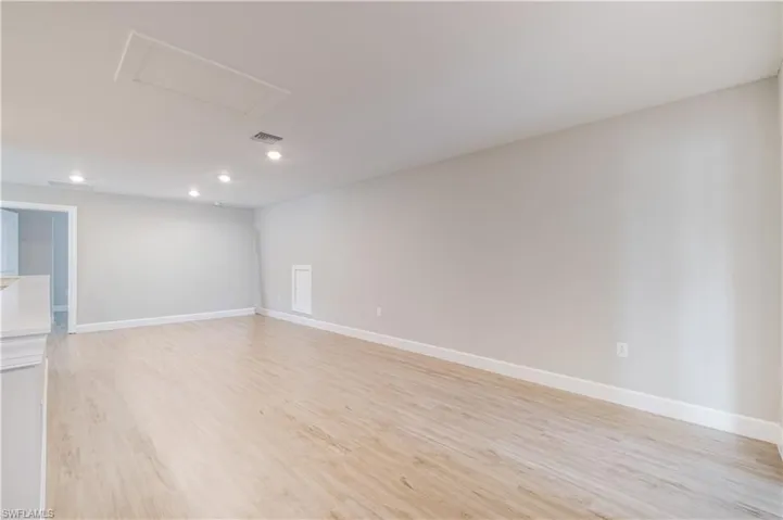 Unfurnished room with light wood-style flooring, recessed lighting, and attic access