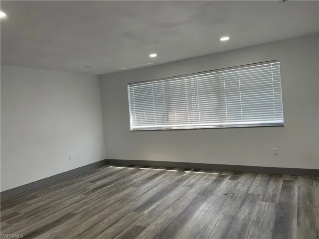 Empty room with dark wood-style floors and recessed lighting