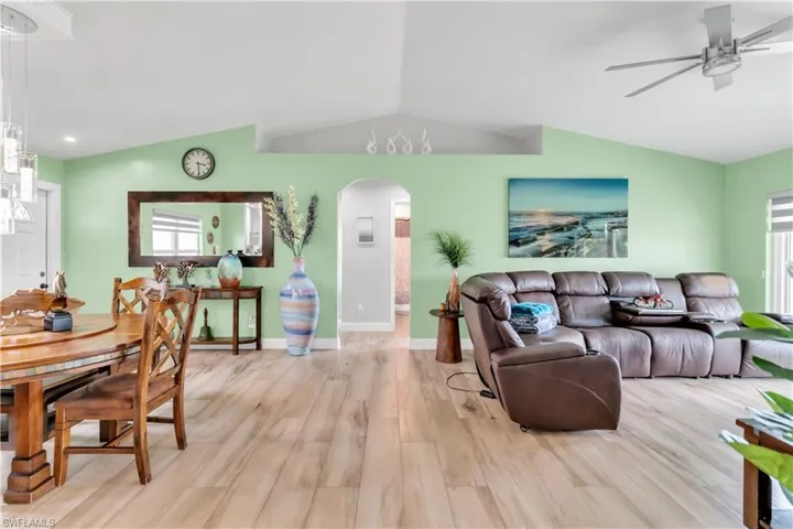 Living room featuring light hardwood / wood-style floors, vaulted ceiling, and ceiling fan