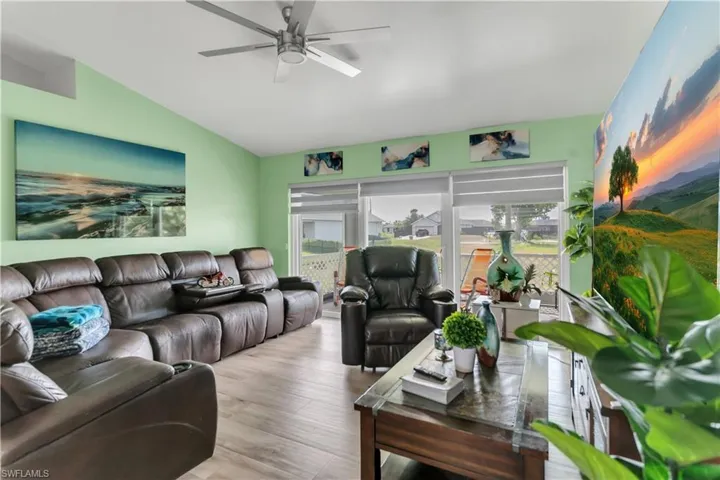 Living room featuring ceiling fan, vaulted ceiling, and light hardwood / wood-style floors