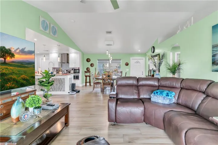 Living room featuring ceiling fan, vaulted ceiling, and light hardwood / wood-style flooring