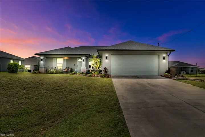 View of front facade with a garage and a yard
