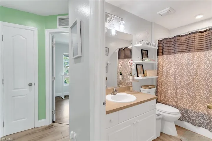 Bathroom with hardwood / wood-style flooring, vanity, walk in shower, and toilet