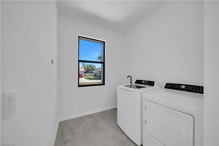 Laundry area featuring washing machine and dryer and light tile patterned flooring