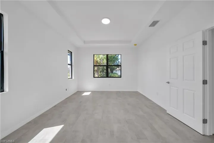 Unfurnished bedroom featuring a raised ceiling and baseboards