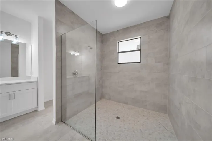 Bathroom featuring vanity, a walk in shower, and light tile patterned floors