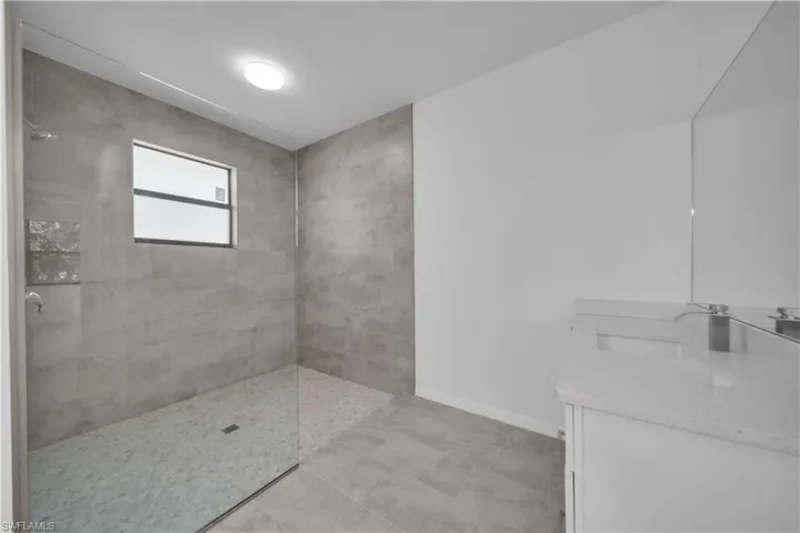 Full bathroom featuring walk in shower, vanity, and light tile patterned floors