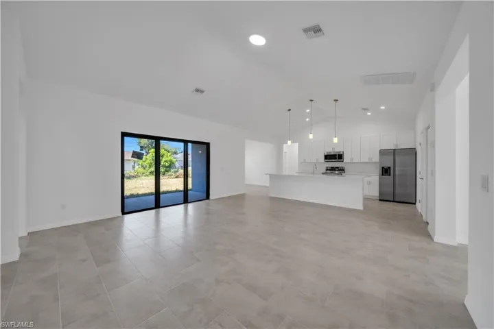 Unfurnished living room featuring vaulted ceiling and recessed lighting