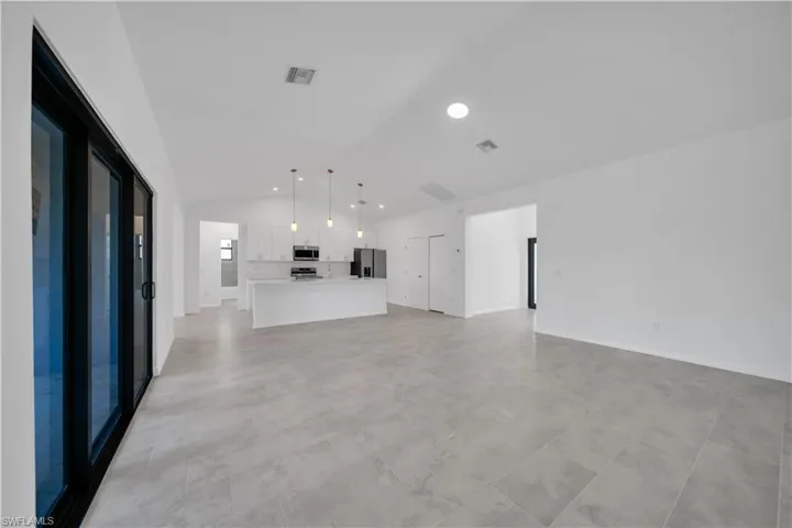 Unfurnished living room featuring lofted ceiling and recessed lighting