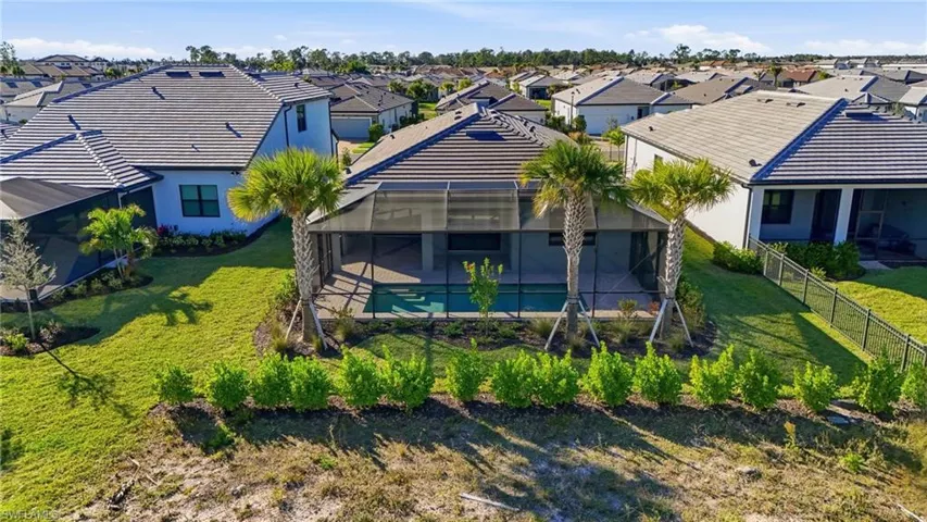 Screened-in pool area featuring a tile roof, paved patio, and established palm trees