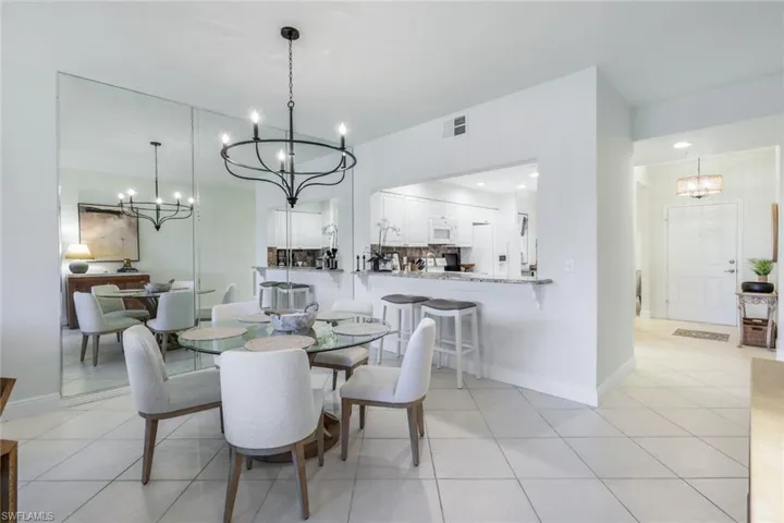 Dining space with a chandelier, light tile patterned flooring, and recessed lighting