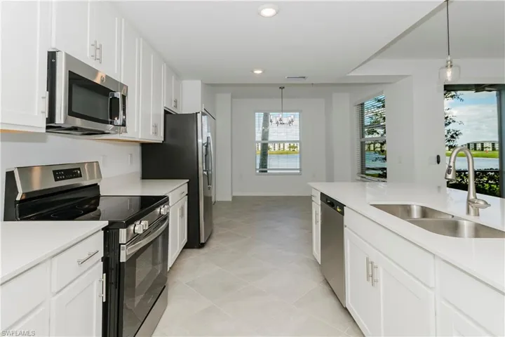 Kitchen featuring stainless steel appliances, white cabinets, and pendant lighting