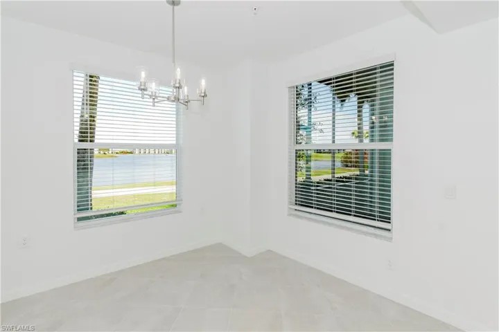 Empty room with suspended lighting, a water view, and light tile patterned flooring