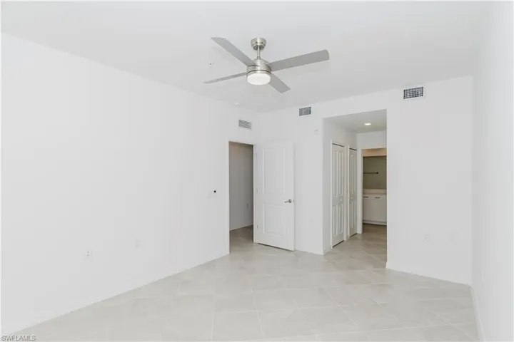 Unfurnished bedroom featuring connected bathroom, a ceiling fan, and a closet