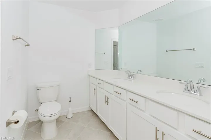 Bathroom with double vanity and light tile patterned flooring