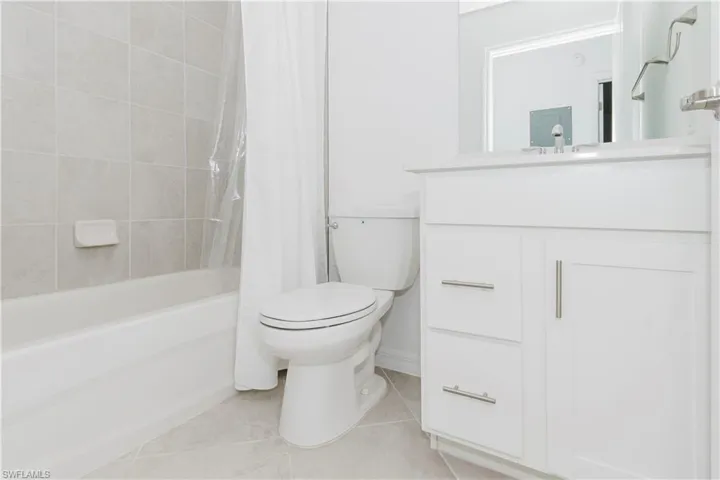 Full bathroom with vanity, shower / tub combo with curtain, and light tile patterned floors
