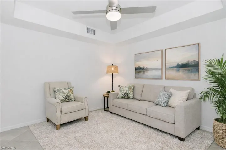 Living room featuring a tray ceiling and a ceiling fan