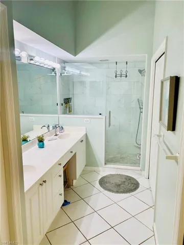 Full bathroom featuring a marble finish shower, double vanity, and tile patterned floors
