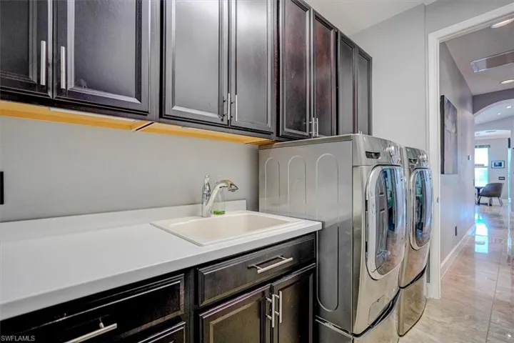 Laundry area with cabinets, washer and clothes dryer, and sink