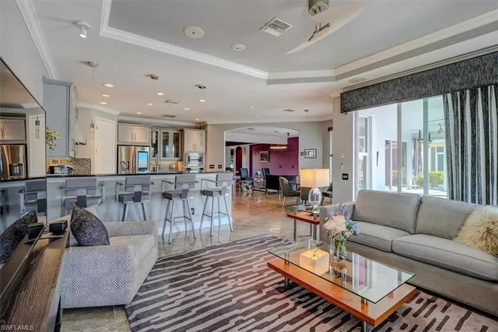Family room featuring breakfast bar, a tray ceiling, ornamental molding, and ceiling fan