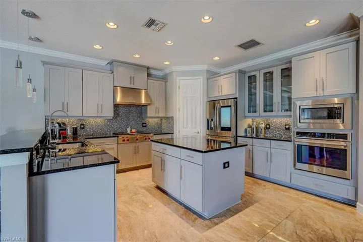Kitchen GAS stove, dark granite countertops, gray cabinetry, ornamental molding, and stainless steel appliances.