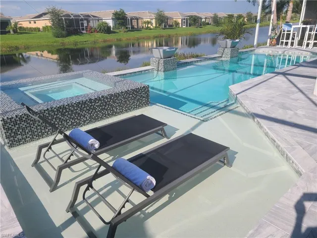 Outdoor pool featuring a residential view, a water view, and an in ground hot tub