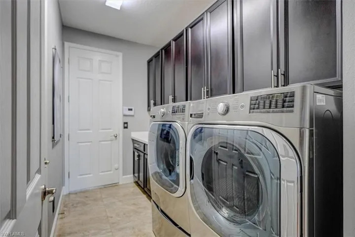 Laundry room with cabinets, light tile patterned flooring, and washer and dryer