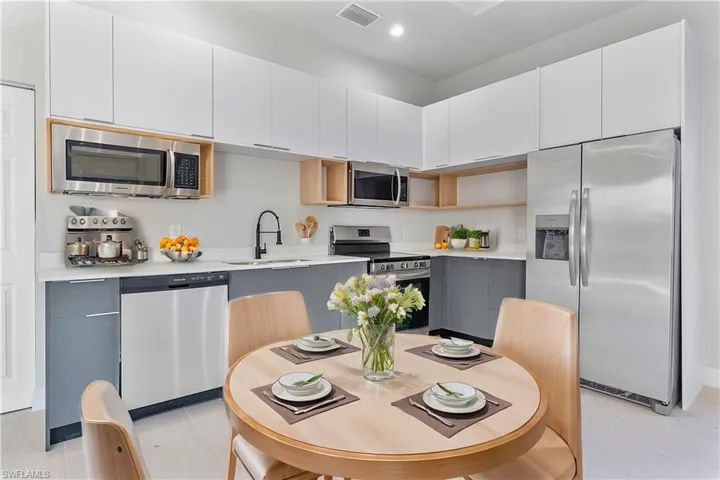 Kitchen with white cabinets, a sink, stainless steel appliances, and light countertops