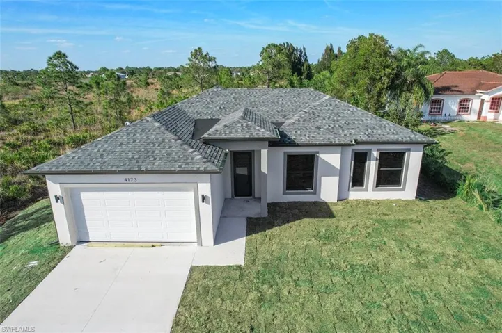 Ranch-style house with an attached garage, driveway, roof with shingles, stucco siding, and a front lawn