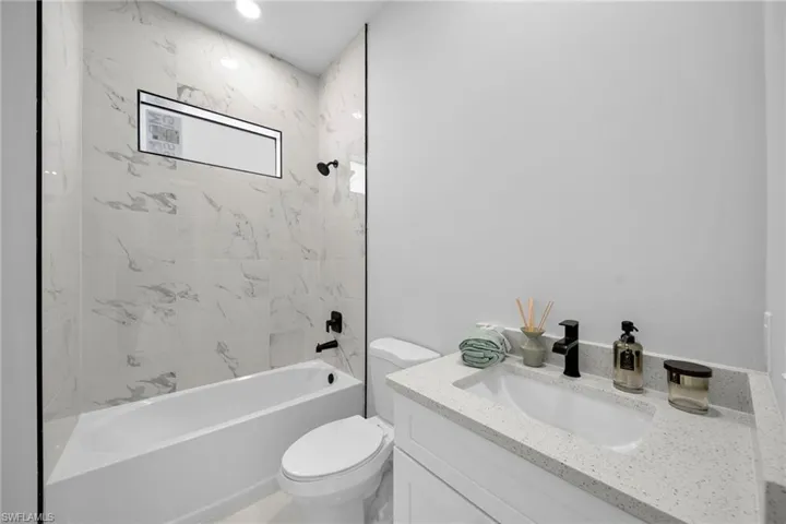 Full bathroom with tiled shower / bath combo, toilet, and vanity