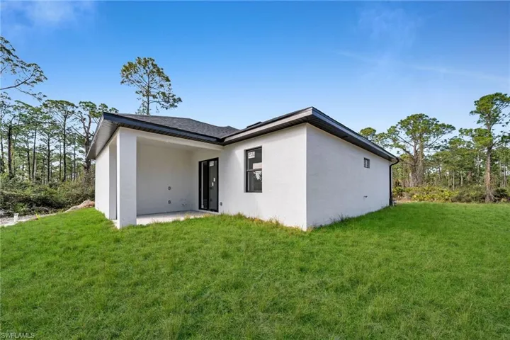 Back of house featuring a lawn and a patio area