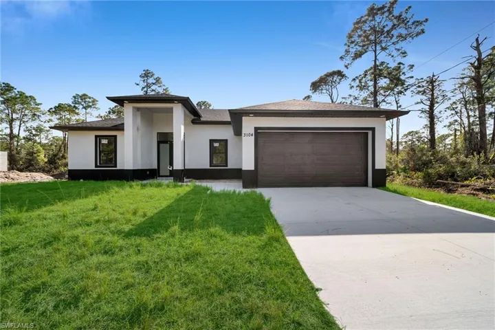 View of front of property featuring a garage and a front lawn