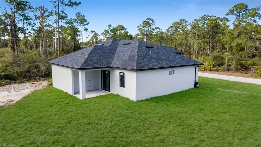 Rear view of property featuring a lawn and a patio