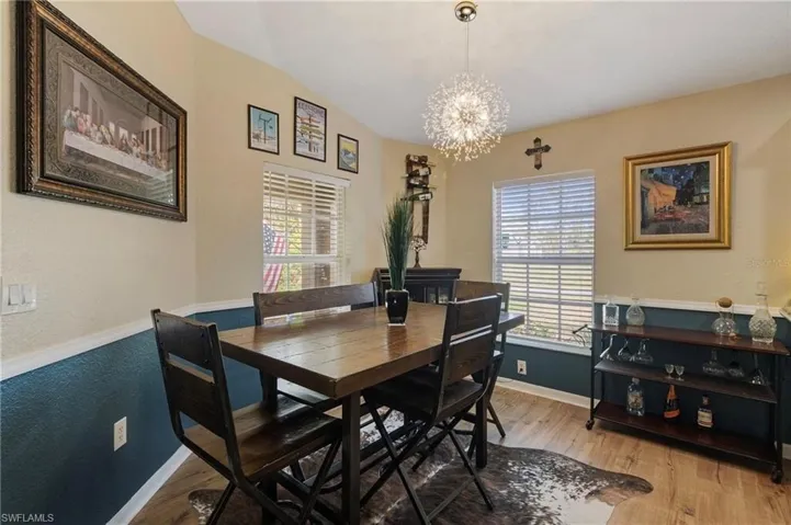 Dining space featuring light wood finished floors, a chandelier, and a textured wall