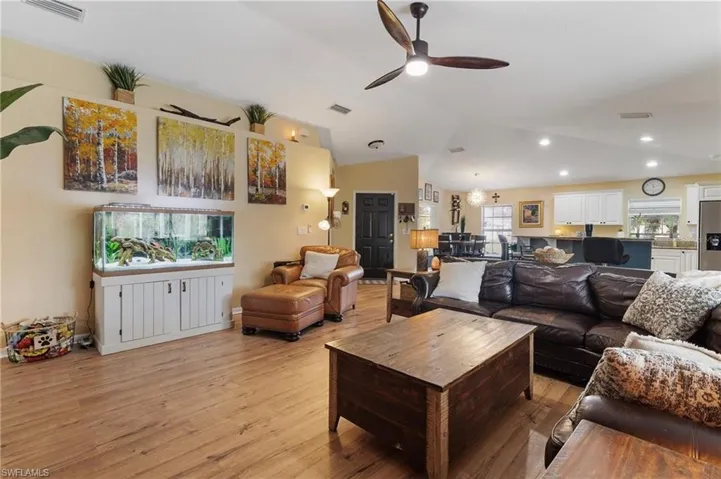 Living room with ceiling fan, light wood-style floors, and vaulted ceiling