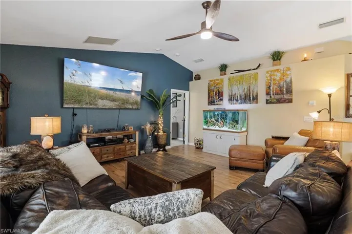 Living area with ceiling fan, wood finished floors, and lofted ceiling