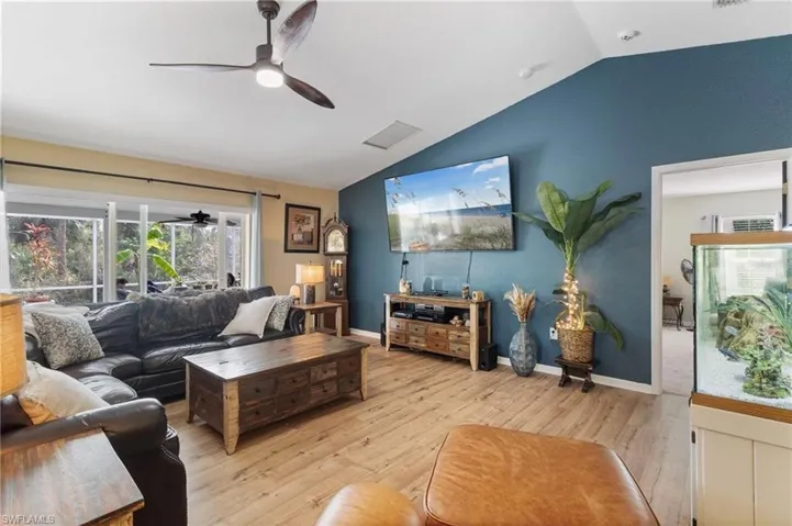 Living room featuring ceiling fan, vaulted ceiling, and hardwood / wood-style flooring