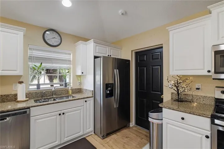 Kitchen featuring stainless steel appliances, white cabinetry, and dark stone counters