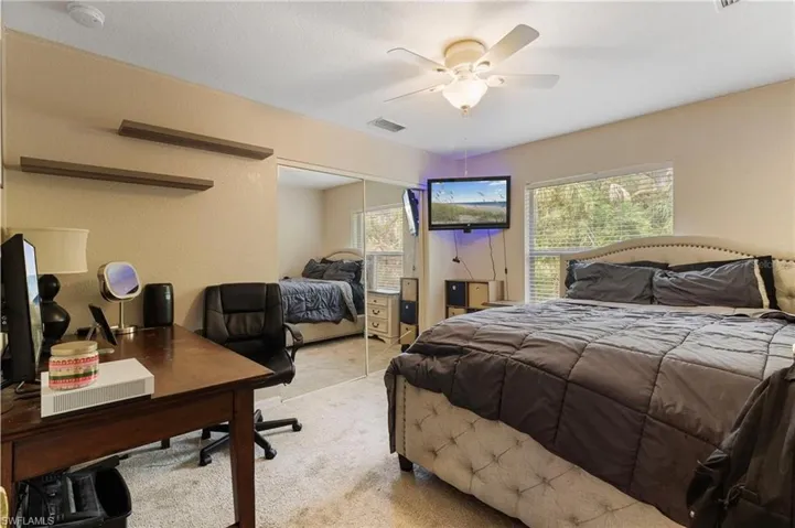 Bedroom with an office area, carpet, ceiling fan, and a closet