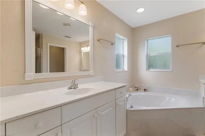 Bathroom with vanity, a garden tub, and a textured wall