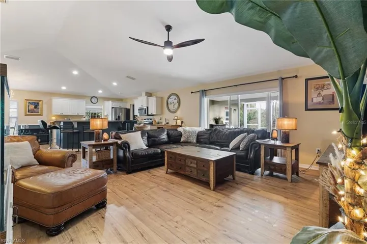 Living area featuring light wood-type flooring, a ceiling fan, healthy amount of natural light, vaulted ceiling, and recessed lighting