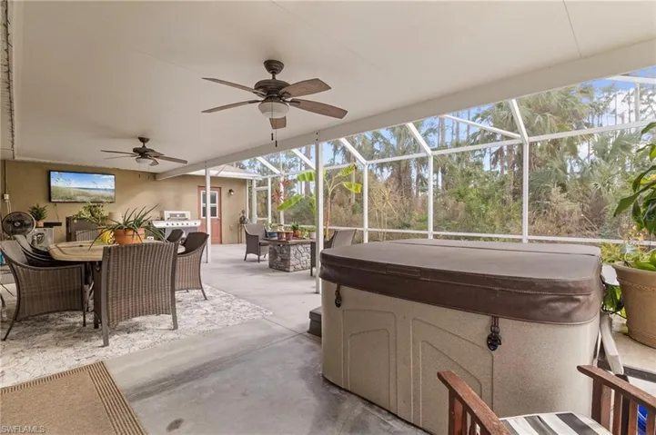 View of patio / terrace with outdoor dining area, a hot tub, ceiling fan, glass enclosure, and a sunroom