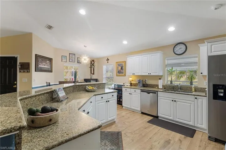 Kitchen featuring stainless steel appliances, white cabinetry, a chandelier, and light stone counters