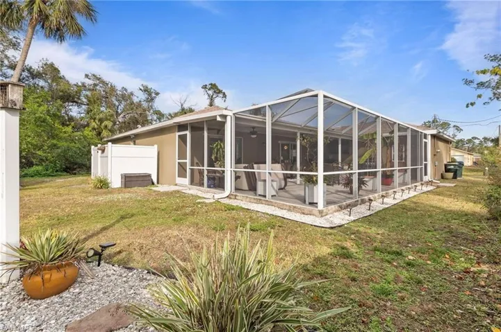 Rear view of house with a yard, glass enclosure, ceiling fan, and a sunroom