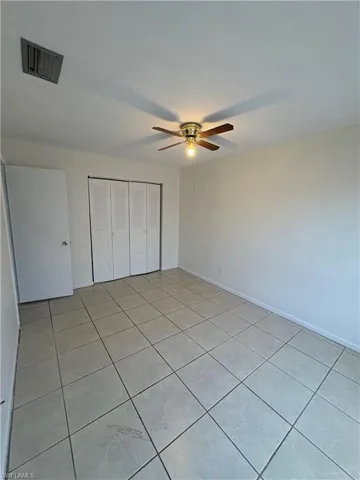 Unfurnished bedroom with a closet, light tile patterned floors, and ceiling fan