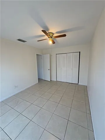 Unfurnished bedroom with light tile patterned flooring, a closet, and a ceiling fan